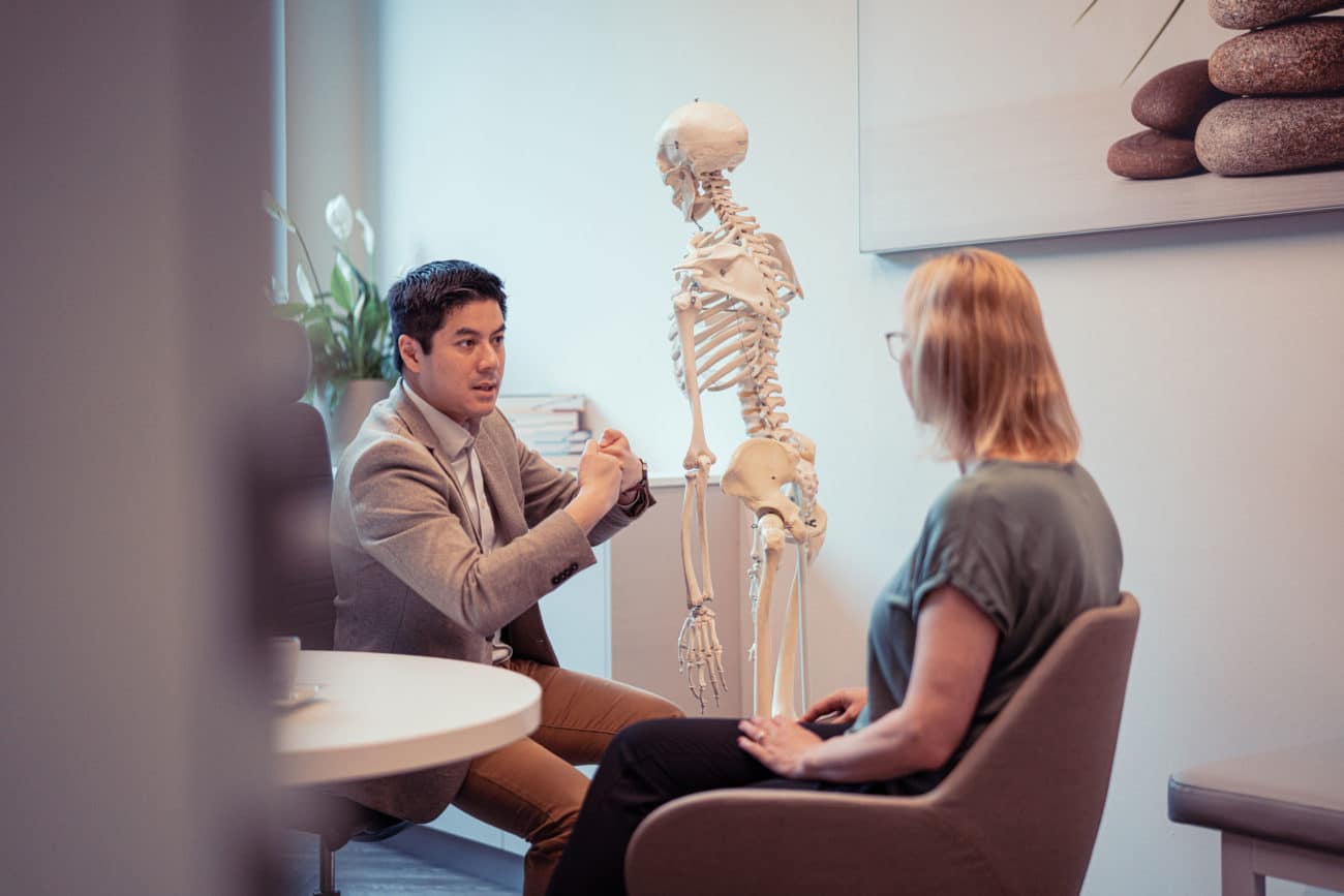 nexmed Radiologe erklärt einer Patienten einen Bandscheibenvorfall am Skelett